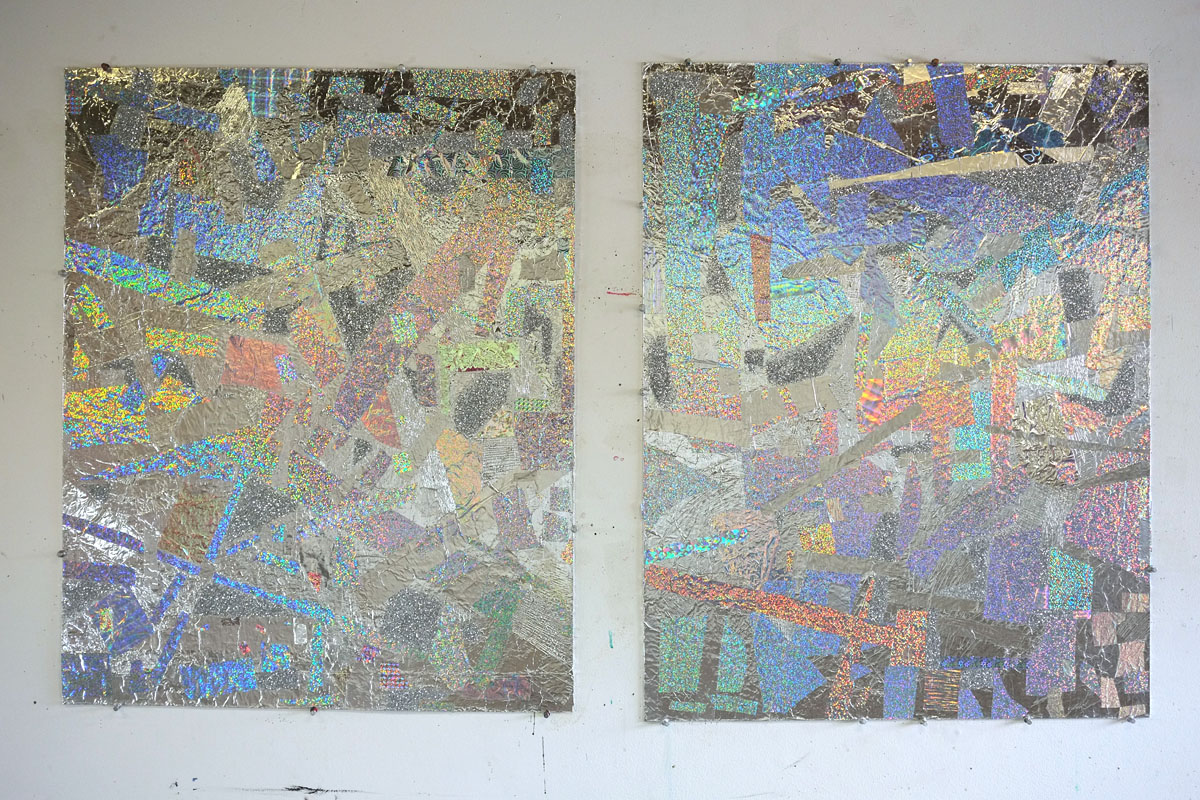 Two silvery glittery paintings with rainbow colored reflections side-by-side on a white wall.